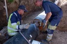 Straßenbauarbeiten: Zwei Männer verlegen die neuen Rohre für das Nahwärmenetz